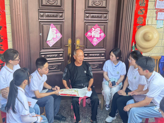 圖為朱流慶拿著父親的烈士證明書給實踐隊員們講述父親的革命故事